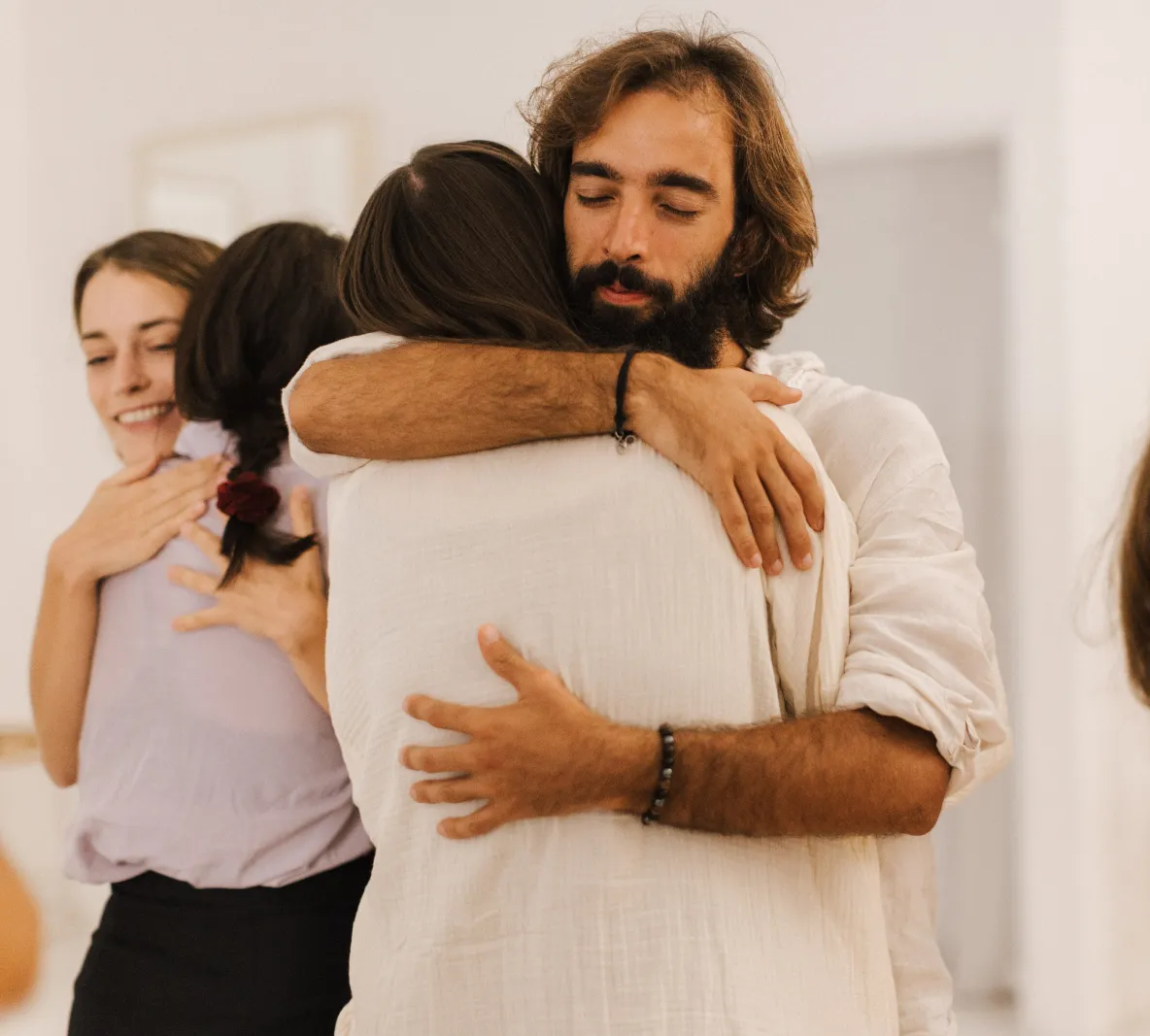 Tiago with his eyes closed, hugging someone in a circle of people dressed in white