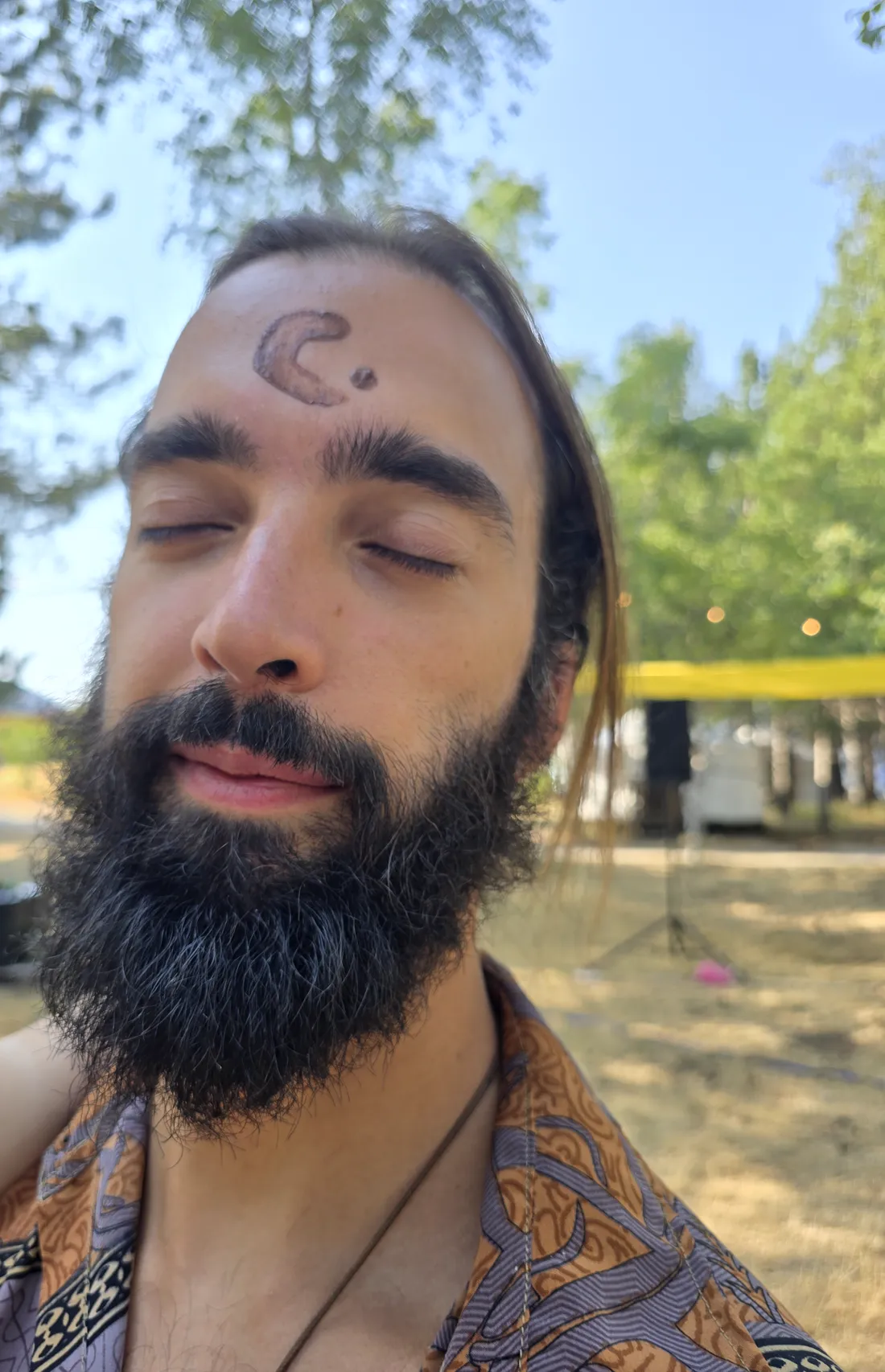 O Tiago de olhos fechados e uma lua desenhada na testa, num encontro de cacau de verão debaixo das árvores